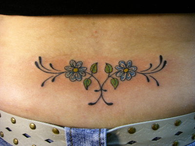 A lower back tattoo displayed with a crop top at an outdoor concert.